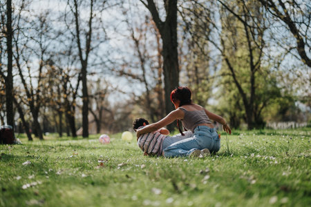 Mother and child playing joyfully on green grass in a sunny park