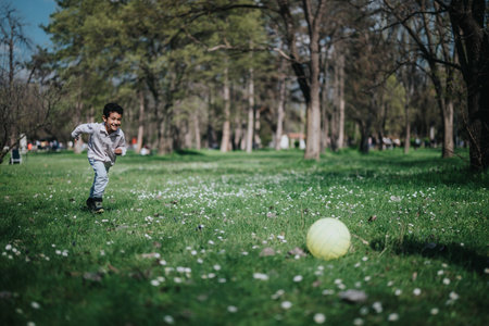Young boy playing with a ball in a lush green park
