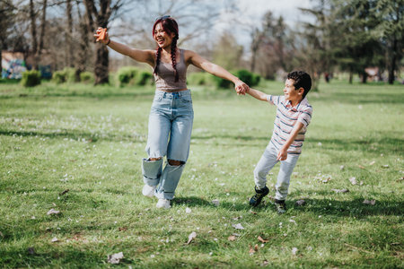 Mother and son holding hands while happily playing in a sunny park field