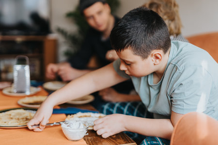 Young boy preparing food at the table with familyの写真素材