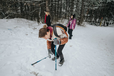 Group of people exploring a snowy forest trail during winter with trekking polesの写真素材