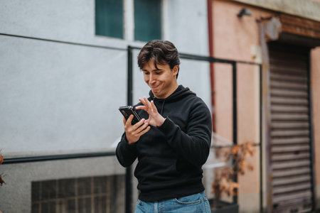 Young man smiling while using a smart phone in an outdoor urban setting