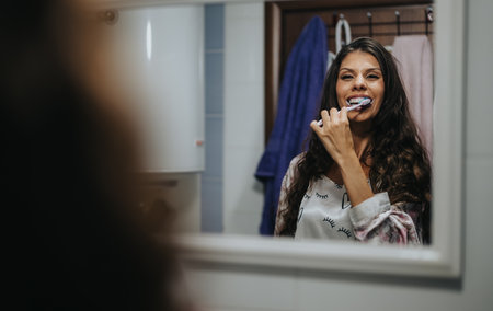 Woman happily brushing teeth in a cozy bathroom setting