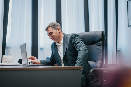 Professional businessman working at his laptop in a modern office settingの写真素材