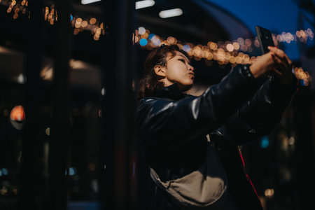 Young woman taking a selfie in dark urban outdoor environmentの写真素材