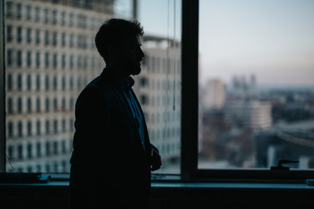 Silhouette of a professional in an urban office setting during twilight