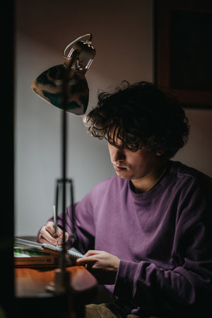 Young person focused on studying under a desk lamp at night