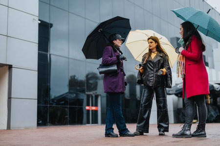 Women enjoying conversation under umbrellas in an urban settingの写真素材