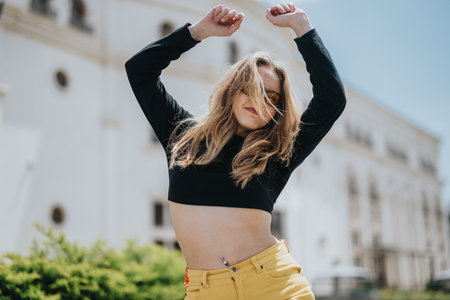 Young woman dancing outdoors in a sunny urban environmentの写真素材