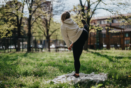 Woman practicing yoga outdoors in a serene park setting on a sunny day