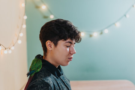 Young woman with a parrot on her shoulder in a cozy roomの写真素材