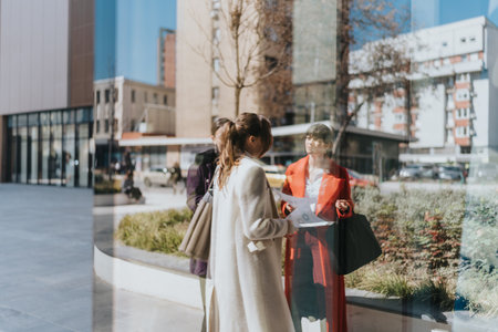 Three professional businesswomen discussing documents outdoors in an urban setting