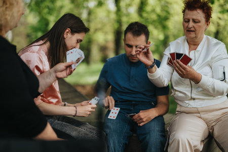 Group of people playing a card game together outdoors in a relaxed social setting