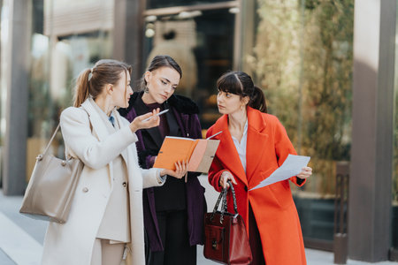 Three professional women discussing documents and ideas in a urban outdoor setting