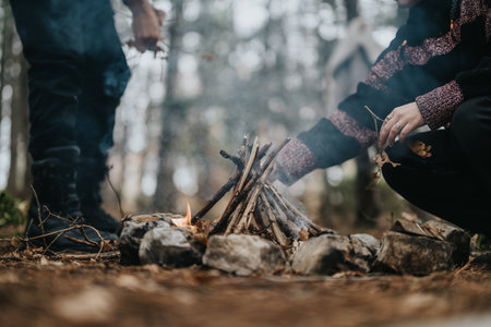 Close-up of People Starting a Fire Outdoors with Sticks and Stones in a Forest Setting