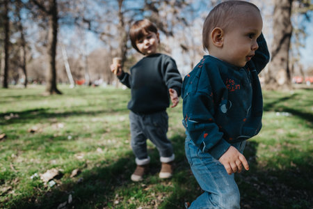 Two young children playing and exploring together outdoors in a park during a bright sunny dayの写真素材