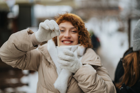 Smiling woman enjoying a hot drink on a snowy winter dayの写真素材