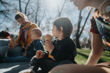 Family enjoying ice cream outdoors during a sunny day surrounded by natureの写真素材