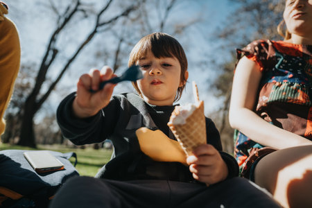Child enjoying ice cream outdoors on a sunny day in the parkの写真素材
