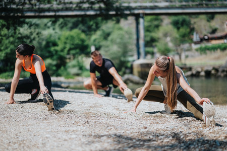 Group of friends exercising and stretching by a scenic riverside location