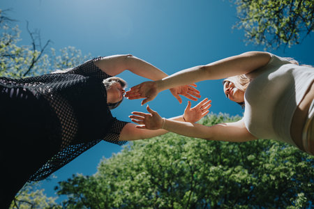 Two friends enjoying a sunny day in the park, interacting and connecting under the open skyの写真素材