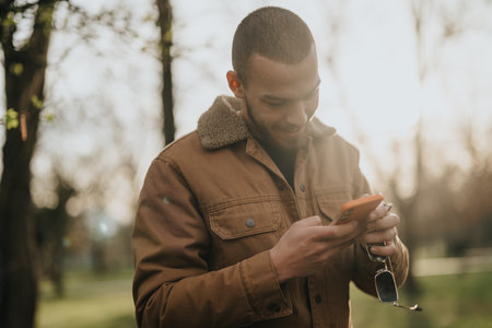 Man enjoying a sunny day while using his phone in the parkの写真素材