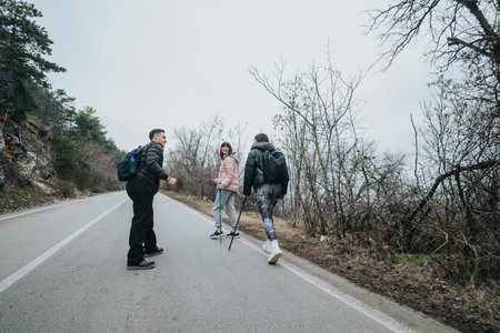 Friends enjoying a hiking trip together on a quiet road surrounded by nature on a cloudy dayの写真素材