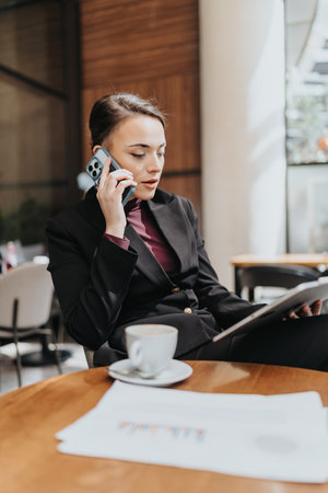 Professional businesswoman multitasking at a cafe with smart phone, tablet, and coffeeの写真素材