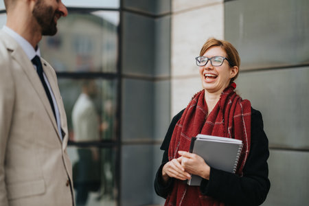 Two business professionals sharing a moment of laughter and conversation outdoorsの写真素材
