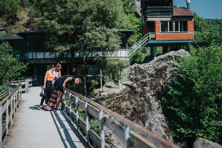 Group of friends exploring nature from a rustic bridge on a summer dayの写真素材