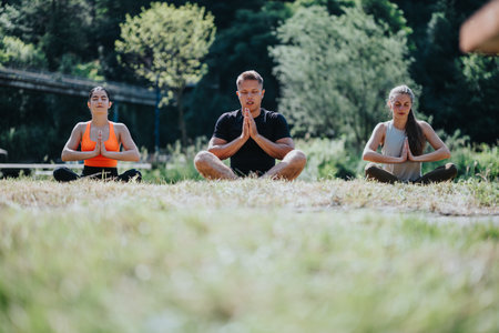 Group practicing yoga outdoors near a scenic riverside forest settingの写真素材