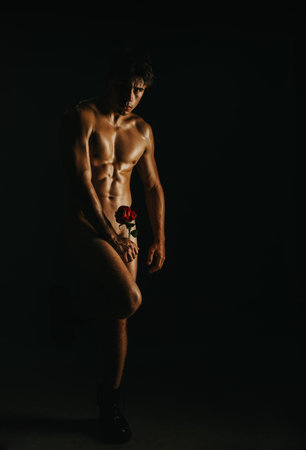 Dramatic low-light portrait of a man with a rose and shadowsの写真素材