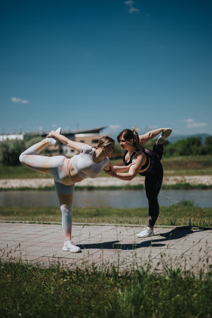 Two women practicing yoga balance poses together outdoors, demonstrating teamwork, creativity, and a passion for health and fitnessの写真素材