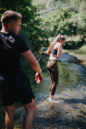 Two people enjoying a refreshing moment in a calm forest water streamの写真素材