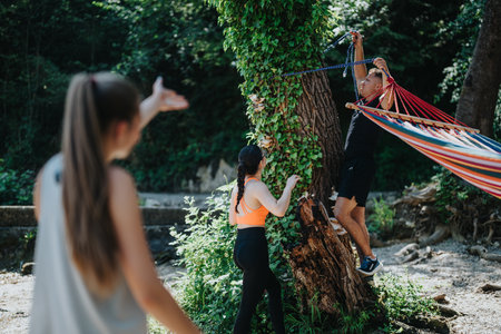 Group of friends setting up a hammock in a lush forestの写真素材