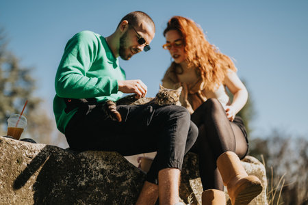 Young couple outdoors bonding and relaxing by playing with a small catの写真素材
