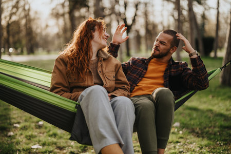 Couple enjoying moments together relaxing on a hammock in a serene parkの写真素材