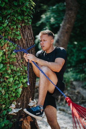 Man tying a rope to a tree trunk in a natural setting