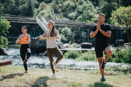 Group yoga practice near a scenic river on a sunny dayの写真素材