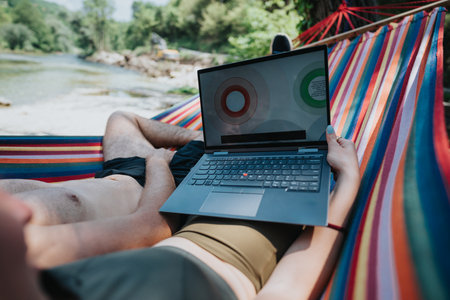 Remote work setup in a hammock outdoors by a scenic riversideの写真素材