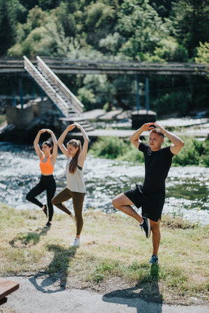 Group practicing yoga poses outdoors by the river on a sunny dayの写真素材