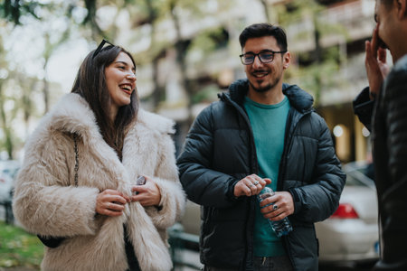 Group of young friends enjoying casual conversation outdoors in autumn clothingの写真素材