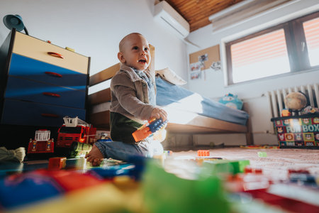 Young child playing joyfully in a sunlit room filled with colorful toys, creating a playful and cheerful atmosphere.の写真素材
