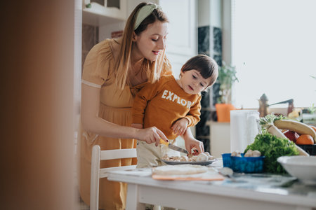 Mother and child preparing food together in a cozy kitchen environmentの写真素材