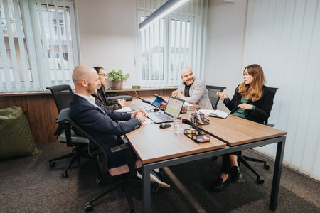 Group of business colleagues engaging in discussion around a table in a modern officeの写真素材
