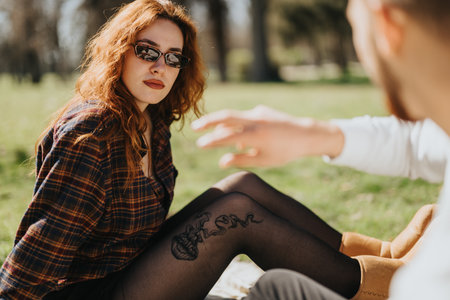 Young woman in sunglasses having a discussion with a companion outdoorsの写真素材