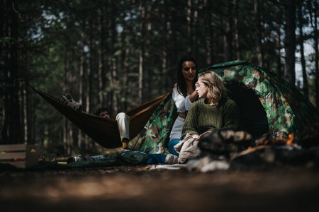 Friends relaxing and enjoying time at a forest campsite with a tentの写真素材