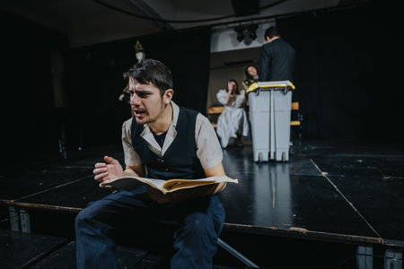 Young actors performing a dramatic scene on a theater stage with expressive gestures and intense emotions.の写真素材