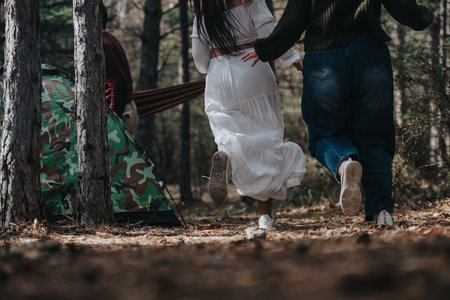 Two friends enjoying a nature hike past a campsite in the woodsの写真素材