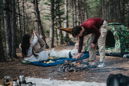 Group enjoying a camping trip with a campfire in a forest settingの写真素材